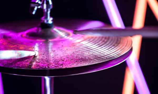 Hi-hat close-up of plates with drumsticks on a background of colored lanterns. Water drops on plates. Musical concept with a working drum.