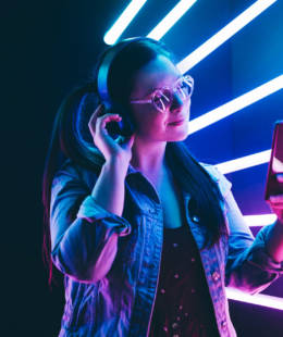 Sillhoutte of hip-hop girl with headphones at the neon light. Fashion portrait of modern young woman making selfie.