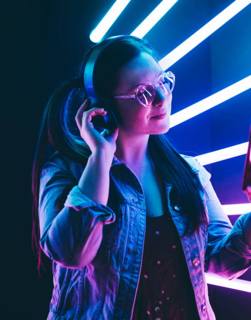 Sillhoutte of hip-hop girl with headphones at the neon light. Fashion portrait of modern young woman making selfie.