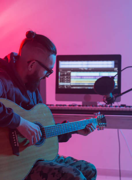 Create music and a recording studio concept - Bearded man guitarist recording electric guitar track in home studio.