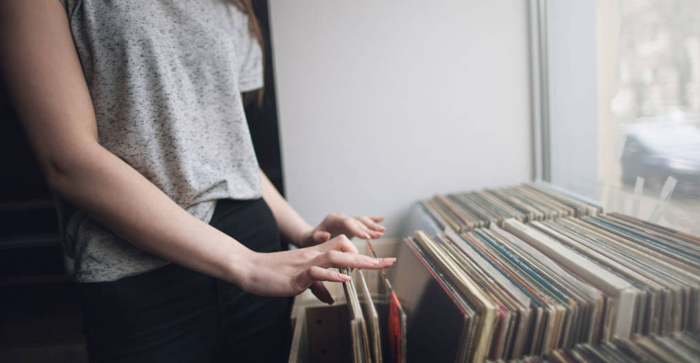 Choosing retro vinyl records. Music background. Unrecognizable woman in musical shop, old school hipster style