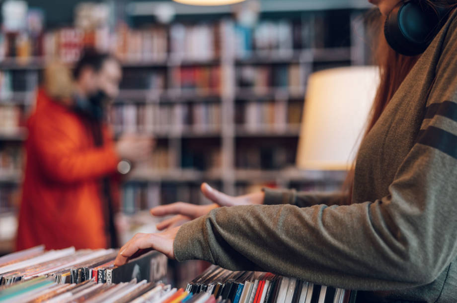 Woman hands selecting records in a shop. Young audiophile hipster woman in a record store. Vintage and retro style. Focus on the hands and a record.