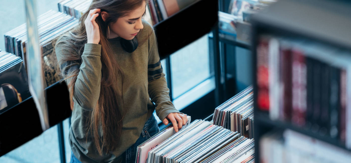 Gorgeous young woman looking for vinyl records in a vintage store. Vintage and retro style.