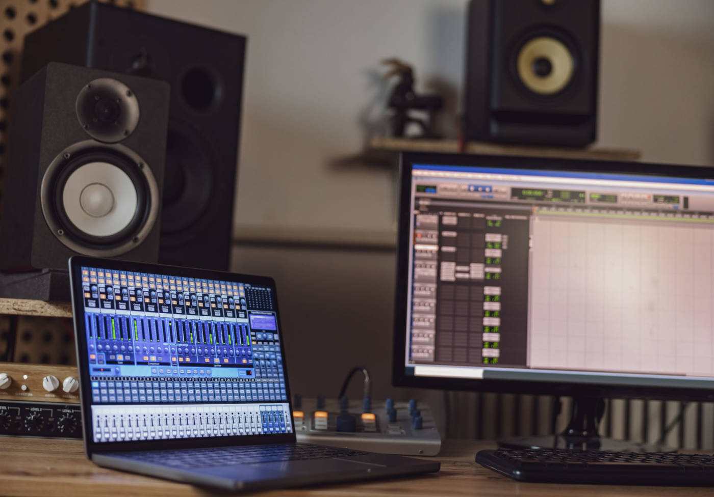 Close-up of switched on laptop and monitor screen on table in the sound engineer room in a broadcasting and recording studio