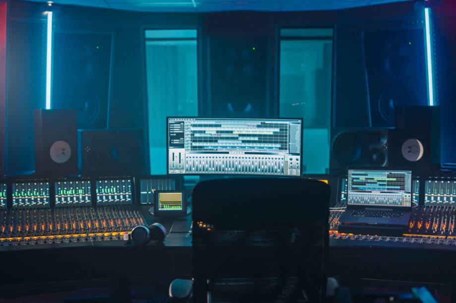 Shot of a Modern Music Record Studio Control Desk with Computer Screen show User Interface of DAW Software with Song Playing. Equalizer, Mixer and other Professional Equipment.