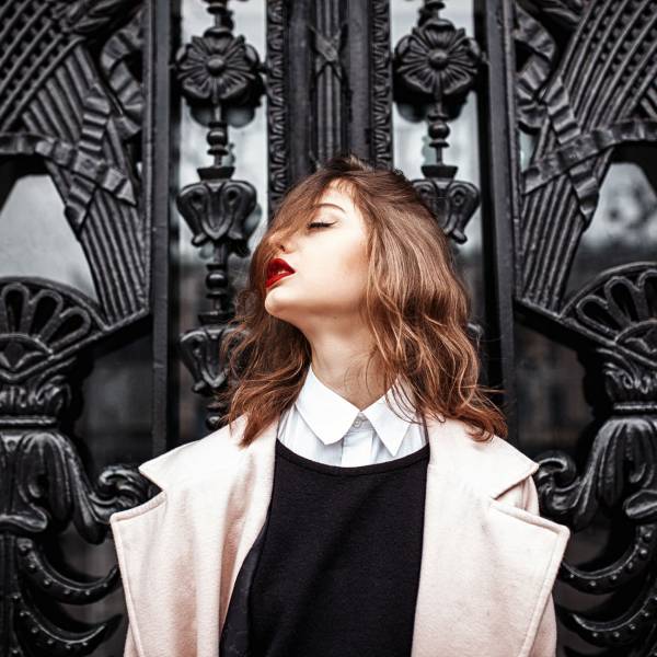 Vintage Street fashion photo. Beautiful young woman in oversize coat and wavy hair outside.