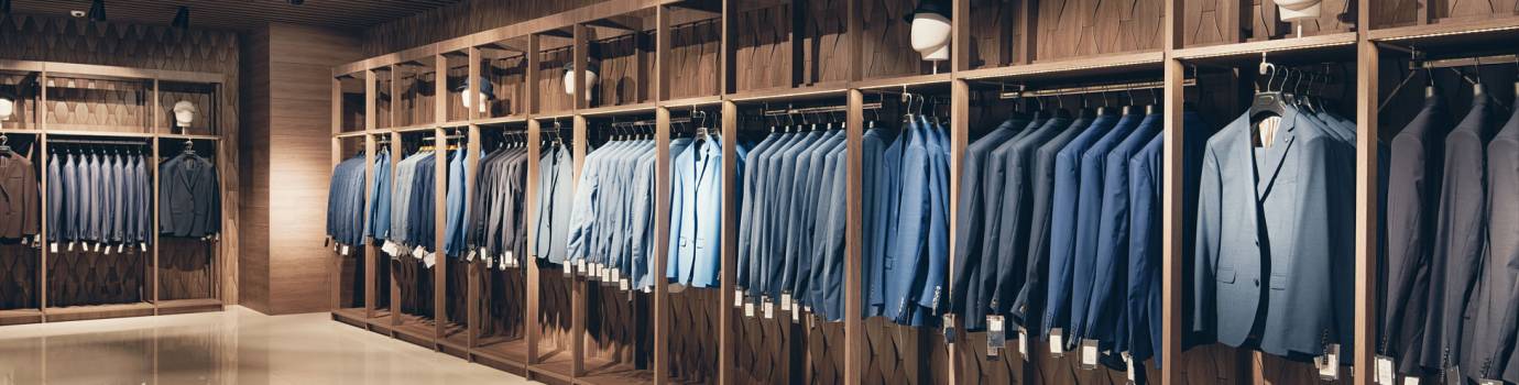 Interior of the business suit shop. Strict premium expensive suits hang in a row on hangers in large quantities