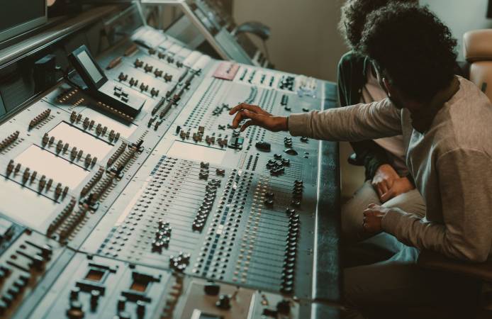 modern musicians working with graphic equalizer at recording studio